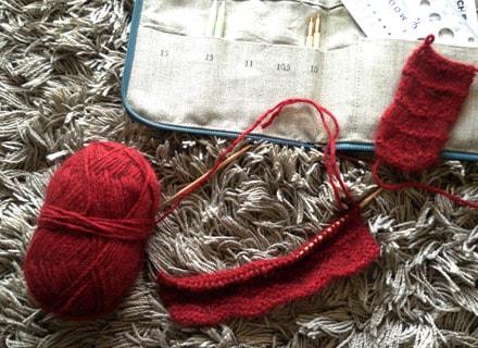 編みかけの赤いリストウォーマーと編み針セット